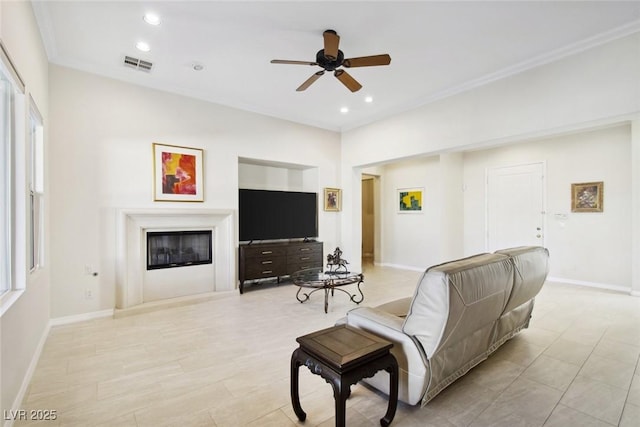 living area with recessed lighting, visible vents, a ceiling fan, a glass covered fireplace, and baseboards