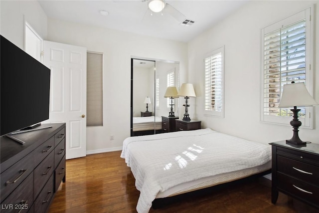 bedroom with ceiling fan, wood finished floors, visible vents, baseboards, and a closet