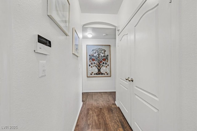 corridor with dark wood-style flooring and baseboards