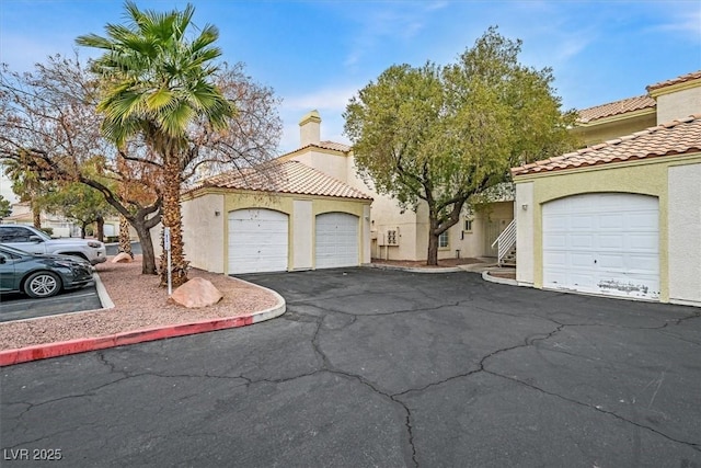 mediterranean / spanish house with a tiled roof, a chimney, and stucco siding