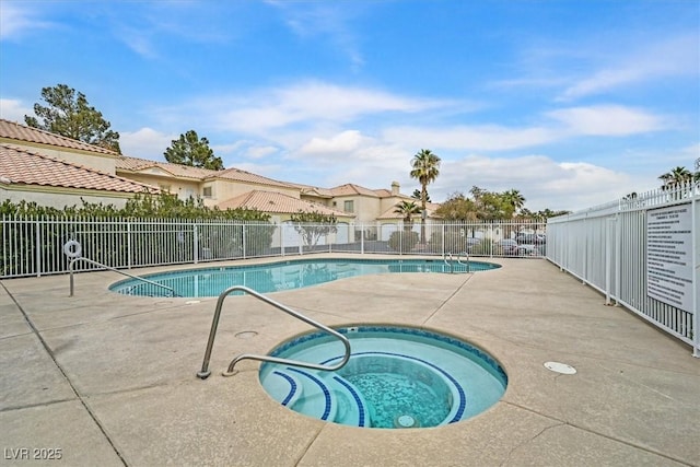 community pool featuring a patio area, fence, a residential view, and a hot tub