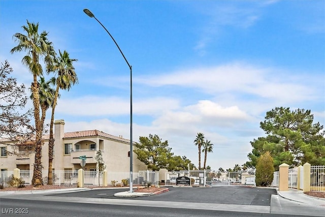 view of street with curbs, a gate, a gated entry, and street lights