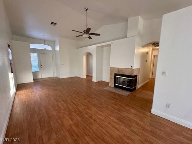 unfurnished living room with ceiling fan, vaulted ceiling, dark wood-type flooring, and a fireplace