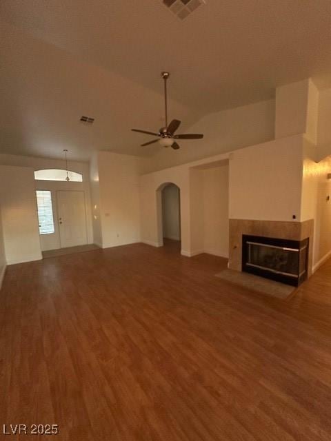 unfurnished living room featuring dark wood-type flooring, ceiling fan, lofted ceiling, and a tile fireplace