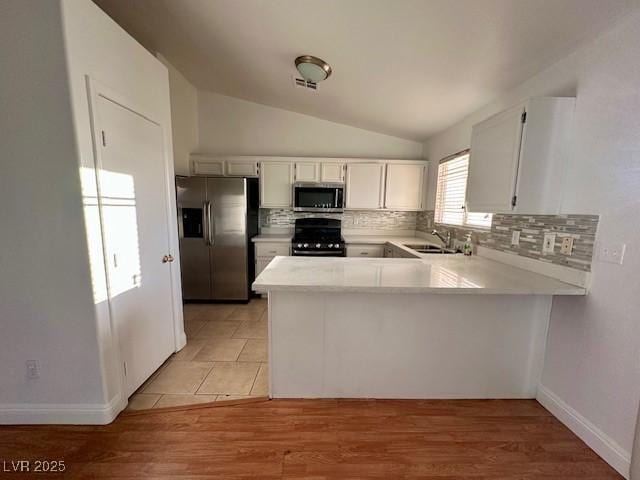 kitchen featuring tasteful backsplash, appliances with stainless steel finishes, white cabinets, and kitchen peninsula