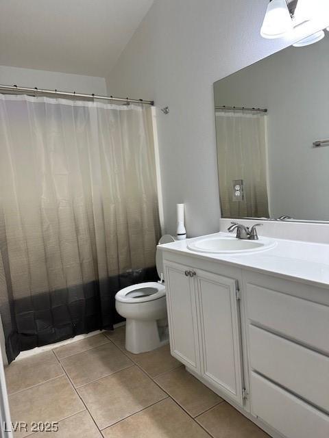 bathroom with vanity, vaulted ceiling, tile patterned floors, and toilet