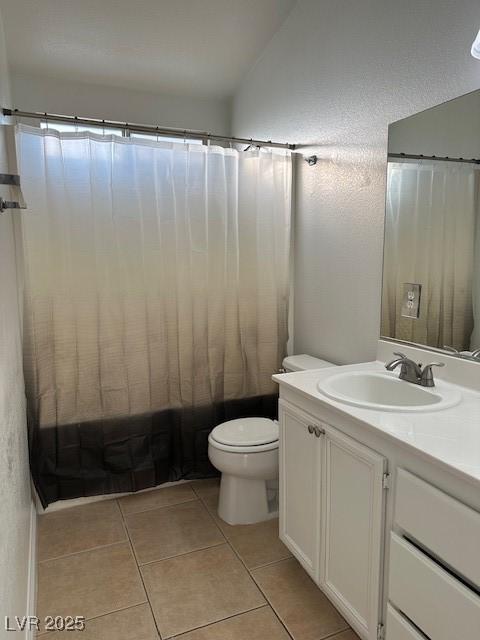 full bathroom featuring vaulted ceiling, shower / tub combo with curtain, vanity, toilet, and tile patterned floors