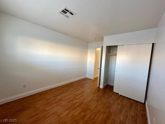 unfurnished bedroom featuring dark hardwood / wood-style flooring and a closet