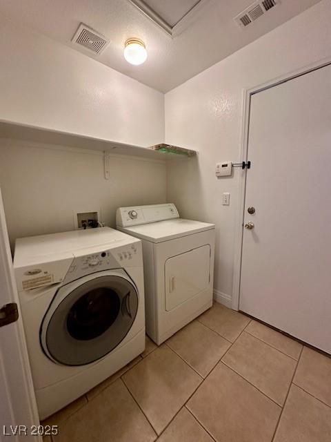 clothes washing area with light tile patterned floors and independent washer and dryer