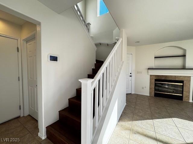 stairs with a tiled fireplace and tile patterned flooring