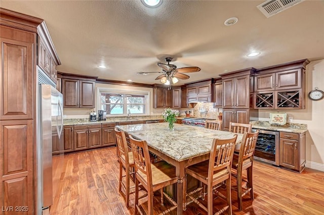 kitchen with sink, a kitchen bar, a center island, light hardwood / wood-style floors, and light stone countertops