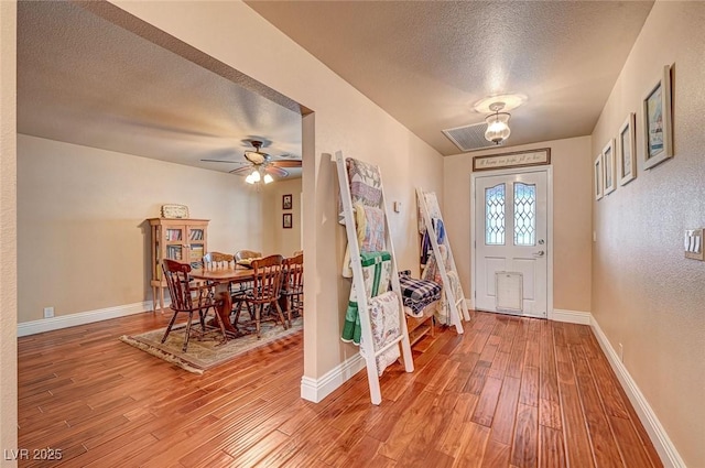 entryway with ceiling fan, wood-type flooring, and a textured ceiling