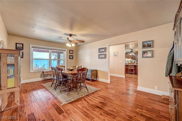 dining space with hardwood / wood-style flooring, a textured ceiling, and ceiling fan