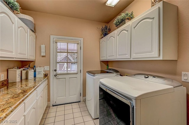 washroom featuring cabinets, washer and dryer, and light tile patterned floors