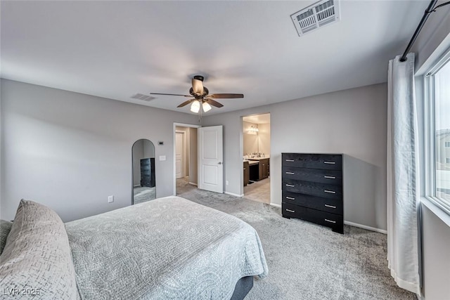 bedroom featuring ceiling fan, ensuite bath, and light carpet