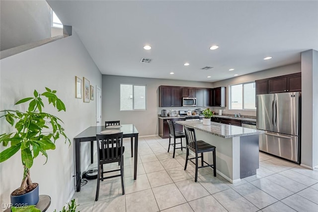 kitchen featuring a center island, dark brown cabinetry, a breakfast bar, and appliances with stainless steel finishes