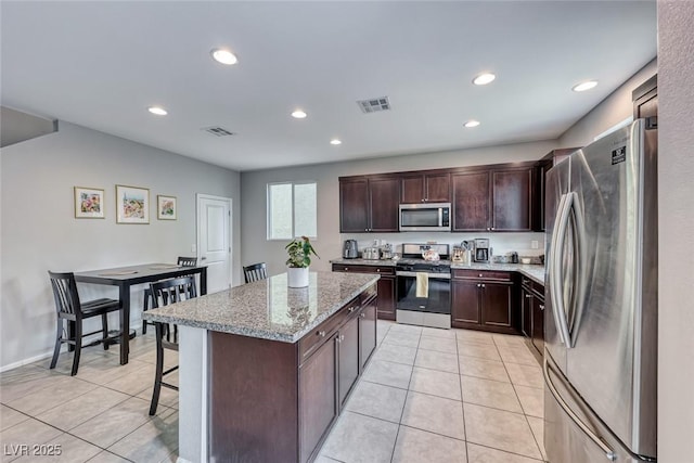 kitchen featuring light tile patterned floors, stainless steel appliances, a breakfast bar, and a kitchen island