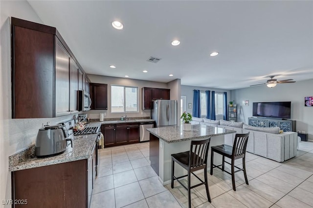 kitchen featuring sink, a breakfast bar area, light stone counters, a kitchen island, and stainless steel appliances