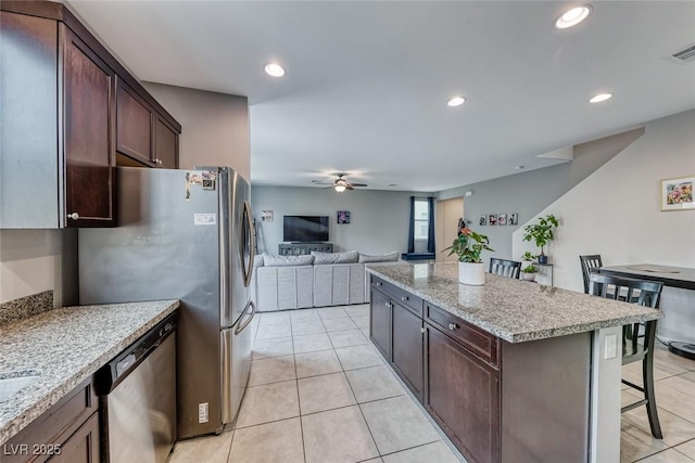 kitchen featuring stainless steel appliances, light stone countertops, a center island, and a kitchen breakfast bar