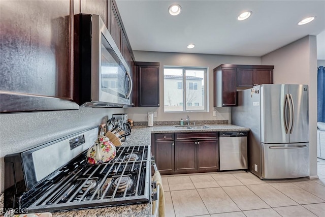 kitchen featuring stainless steel appliances, light tile patterned flooring, dark brown cabinets, and sink