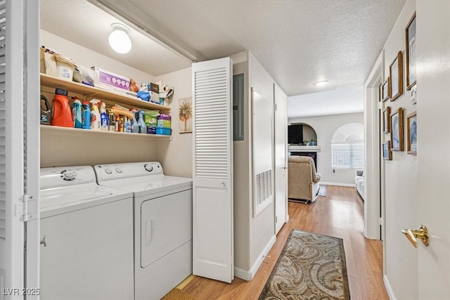 laundry room with washer and clothes dryer, light hardwood / wood-style floors, and a textured ceiling