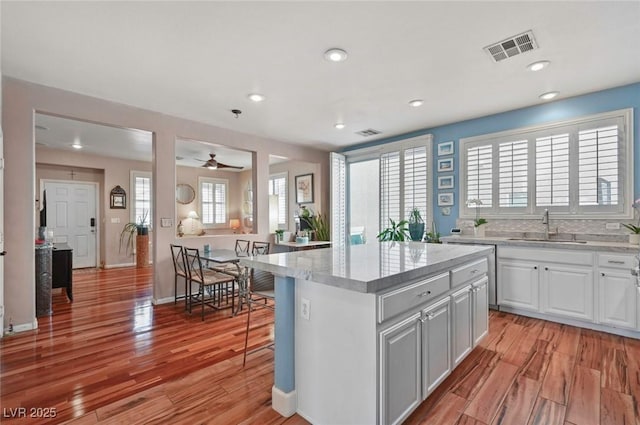 kitchen featuring white cabinetry, sink, a kitchen island, and light wood-type flooring