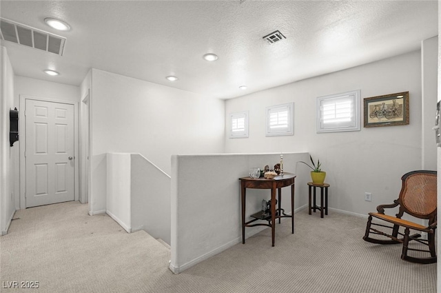 hallway featuring light carpet and a textured ceiling