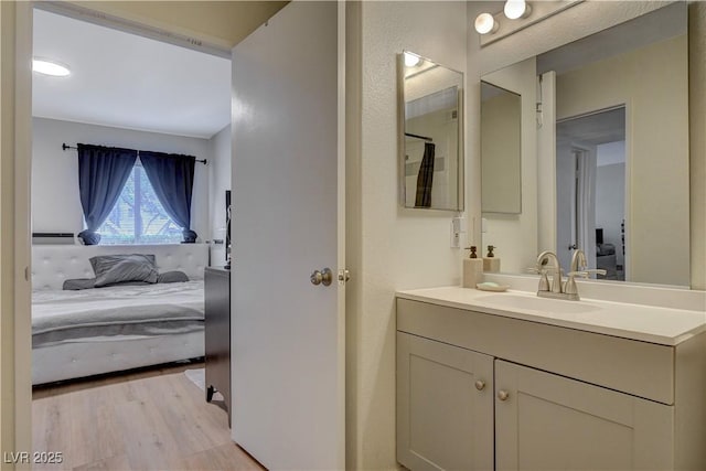 ensuite bathroom with a baseboard radiator, vanity, connected bathroom, and wood finished floors