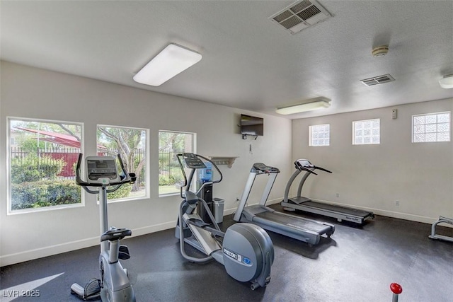 workout room with a textured ceiling, visible vents, and baseboards