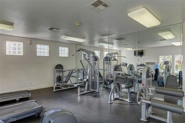 exercise room with baseboards, visible vents, and a healthy amount of sunlight