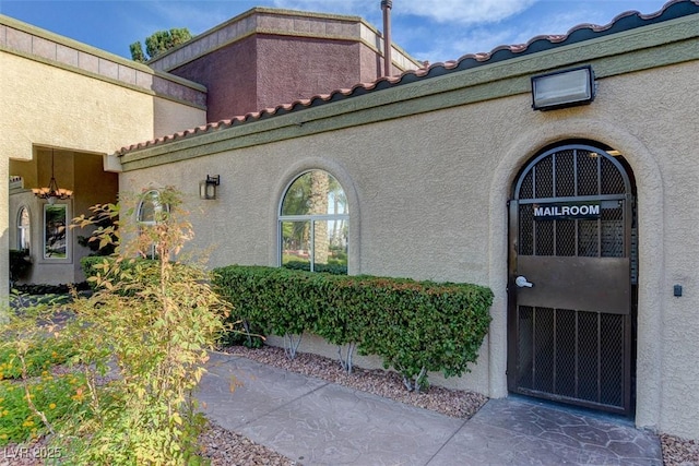 doorway to property with a tile roof and stucco siding