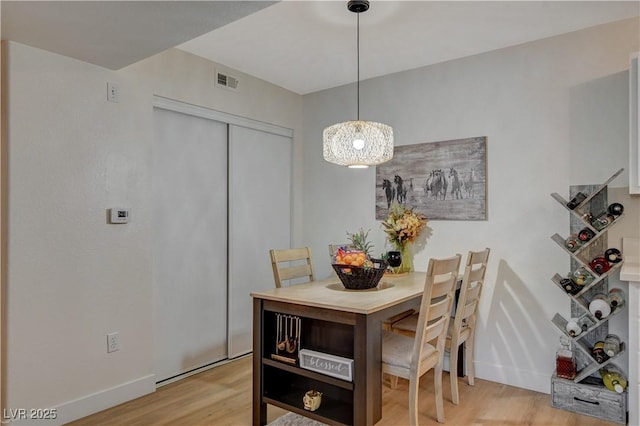 dining space featuring light wood-style flooring, visible vents, and baseboards