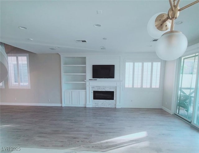 unfurnished living room with wood-type flooring and built in shelves