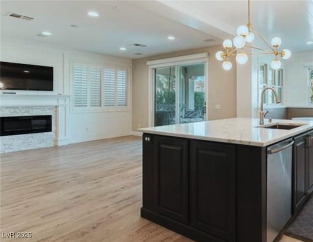 kitchen with sink, hanging light fixtures, light hardwood / wood-style flooring, dishwasher, and a kitchen island with sink