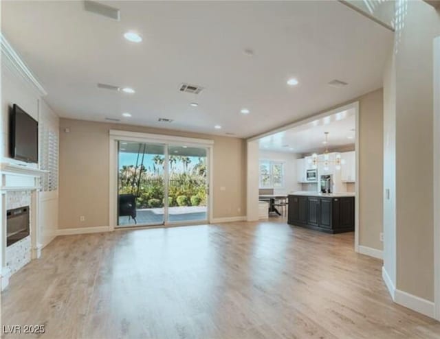 unfurnished living room featuring light wood-type flooring, a fireplace, and baseboards