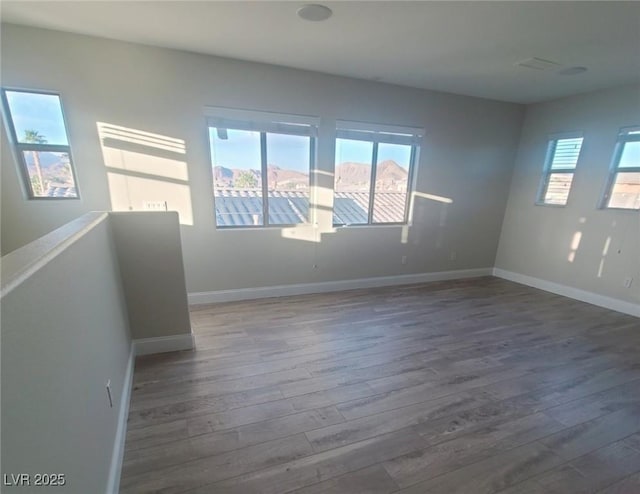 spare room featuring baseboards and dark wood-style flooring