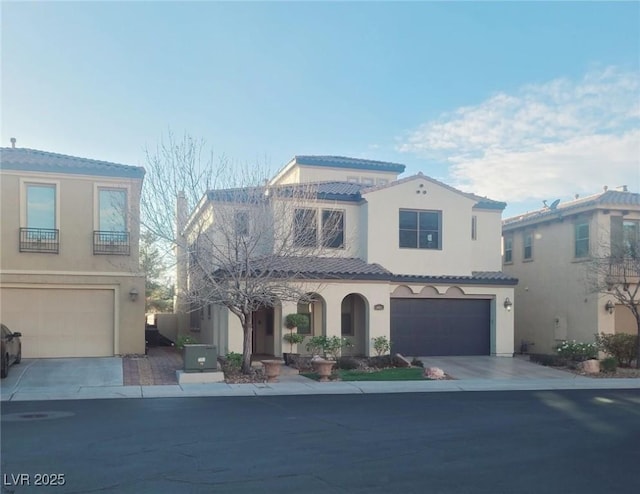 mediterranean / spanish-style home featuring a garage, concrete driveway, and stucco siding