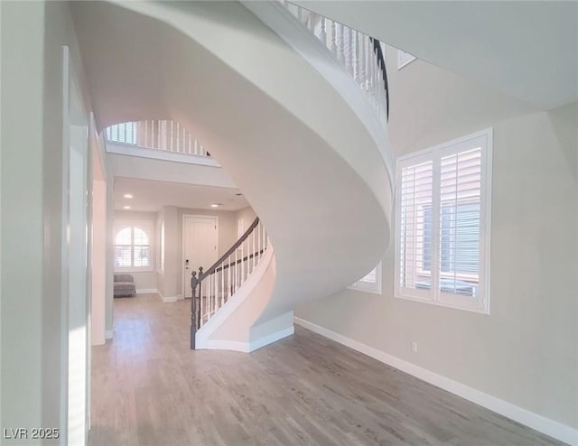 entryway with a towering ceiling and wood-type flooring