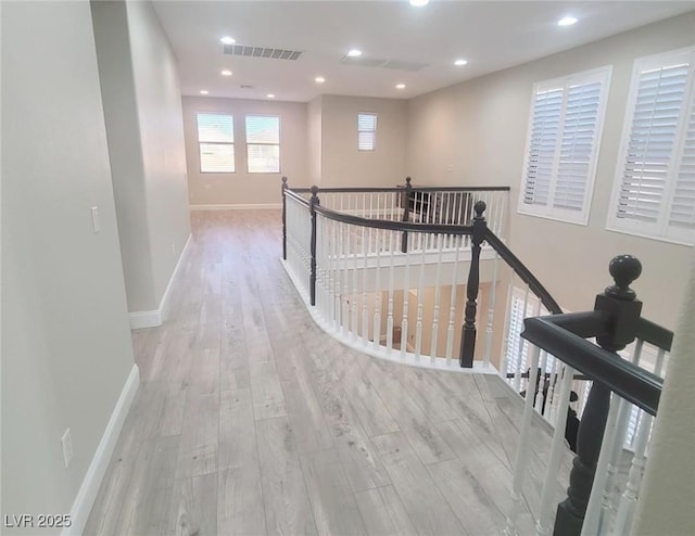 corridor featuring recessed lighting, wood finished floors, an upstairs landing, visible vents, and baseboards