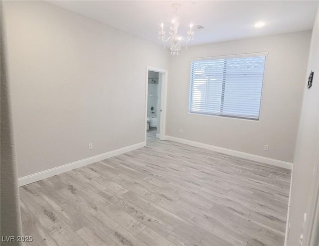 empty room featuring light wood-type flooring, an inviting chandelier, and baseboards