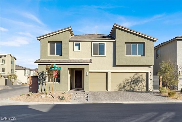 view of front of home featuring a garage, decorative driveway, and stucco siding