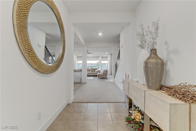 corridor featuring light tile patterned floors, light colored carpet, and baseboards