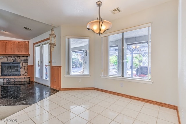 unfurnished dining area with light tile patterned flooring, a stone fireplace, and lofted ceiling