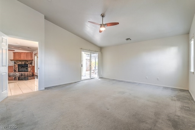 empty room featuring ceiling fan, high vaulted ceiling, light carpet, and a fireplace