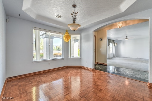 spare room with parquet floors, a tray ceiling, a textured ceiling, and ceiling fan