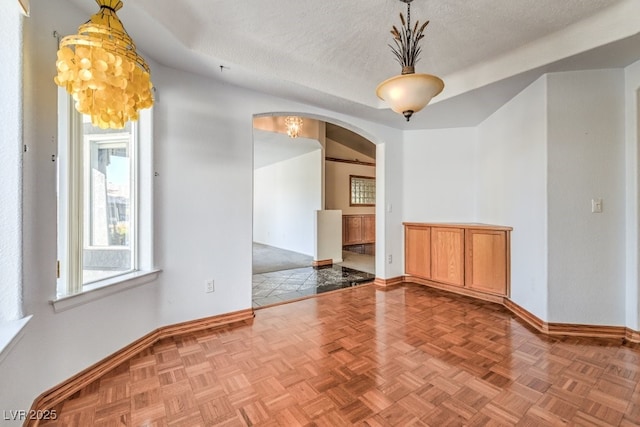 unfurnished room with parquet floors and a textured ceiling