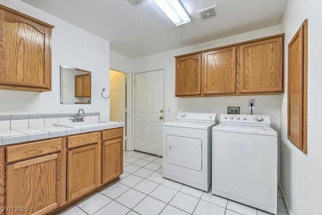 clothes washing area featuring cabinets, washer and dryer, sink, and light tile patterned floors