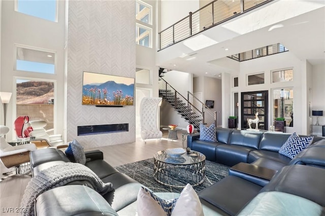 living room featuring wood-type flooring, a tiled fireplace, and a high ceiling