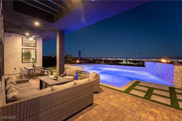 pool at twilight with a patio area, outdoor lounge area, and an in ground hot tub