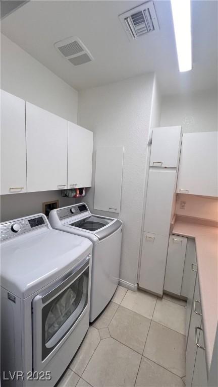 laundry room with cabinets, washer and dryer, and light tile patterned floors